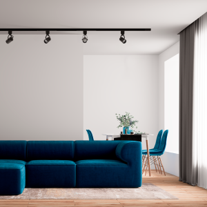 A imagem apresenta uma sala de estar moderna e bem iluminada com Spots para Trilho LILLE instalados em um trilho no teto. Os spots oferecem uma iluminação direcional sobre áreas-chave da sala, destacando-se sobre um sofá azul vibrante e uma área de jantar ao fundo com cadeiras da mesma cor. A atmosfera é contemporânea e convidativa, com os spots adicionando um toque de sofisticação ao ambiente através de sua iluminação prática e estilosa.