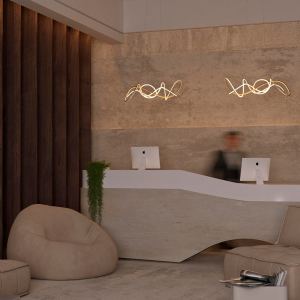 Contemporary reception area with a curved white desk, two iMacs, sculptural pendant lights, and beige lounge seating.