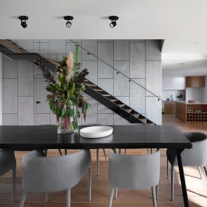 A imagem exibe o Spot De Sobrepor CLASSIC, uma opção de iluminação elegante que combina perfeitamente com a decoração contemporânea da sala de jantar. Os spots, com seu design clássico e acabamento preto, estão dispostos sobre o teto, proporcionando uma luz direcionada que realça a área da mesa, oferecendo uma experiência visual confortável e acentuando a beleza natural da composição do espaço.