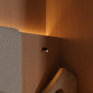 Wood-paneled wall with warm lighting, a small adjustable spotlight, and a beige sculptural chair in the foreground.
